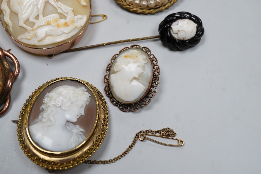 A collection of shell cameo brooches, comprising: a cameo depicting Bacchus, in a gold mount in the Archaeological Revival style, decorated with rope twist and a twisted knife wire border, length 4.4cm; together with sev